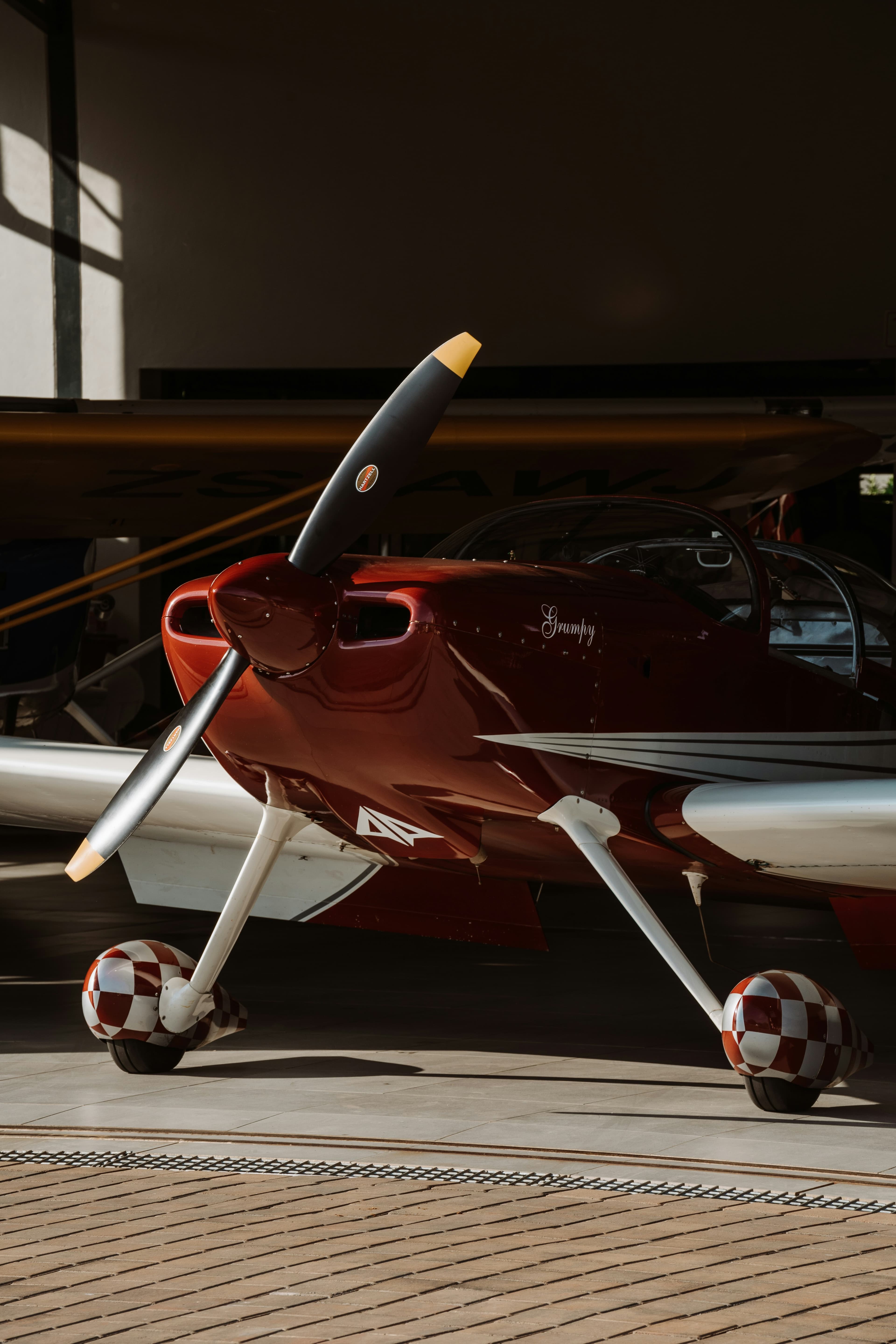 Deep-red checkered-wheel general aviation prop plane parked in a sunlit Colorado hangar